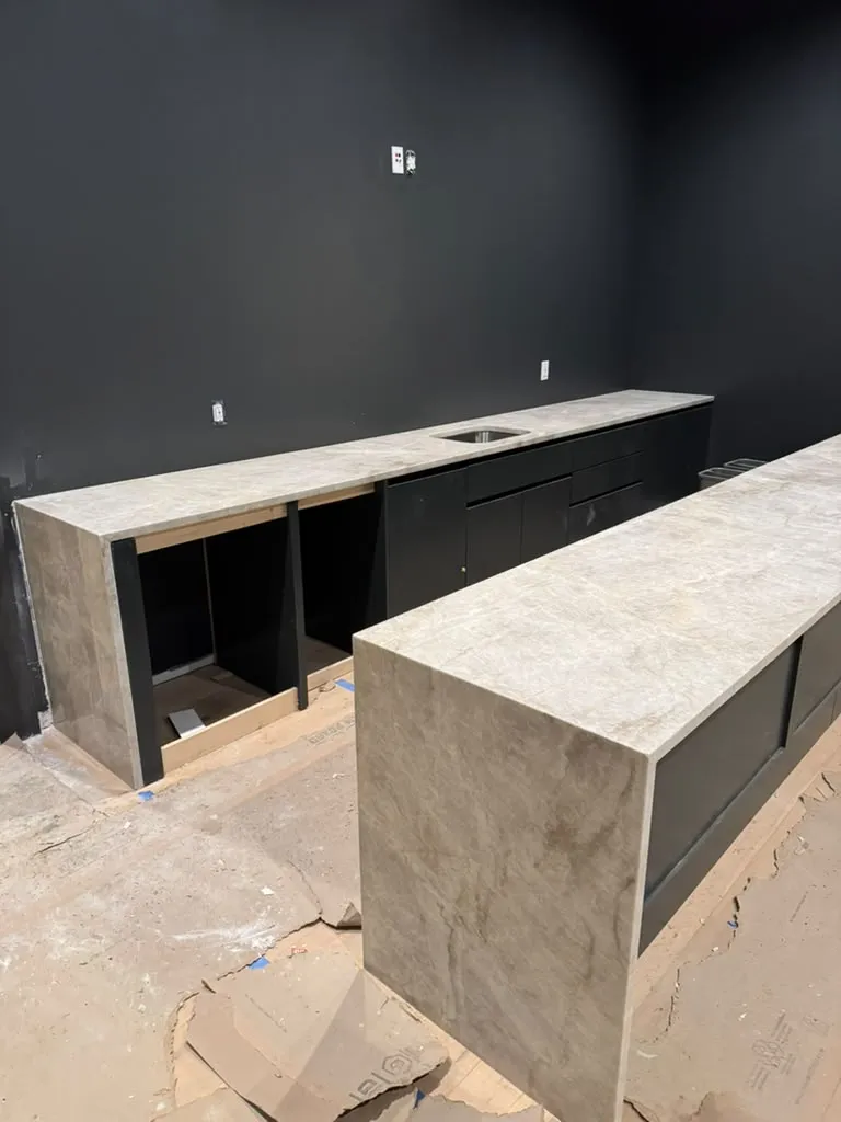 Home bar with a dark stone countertop and waterfall edge